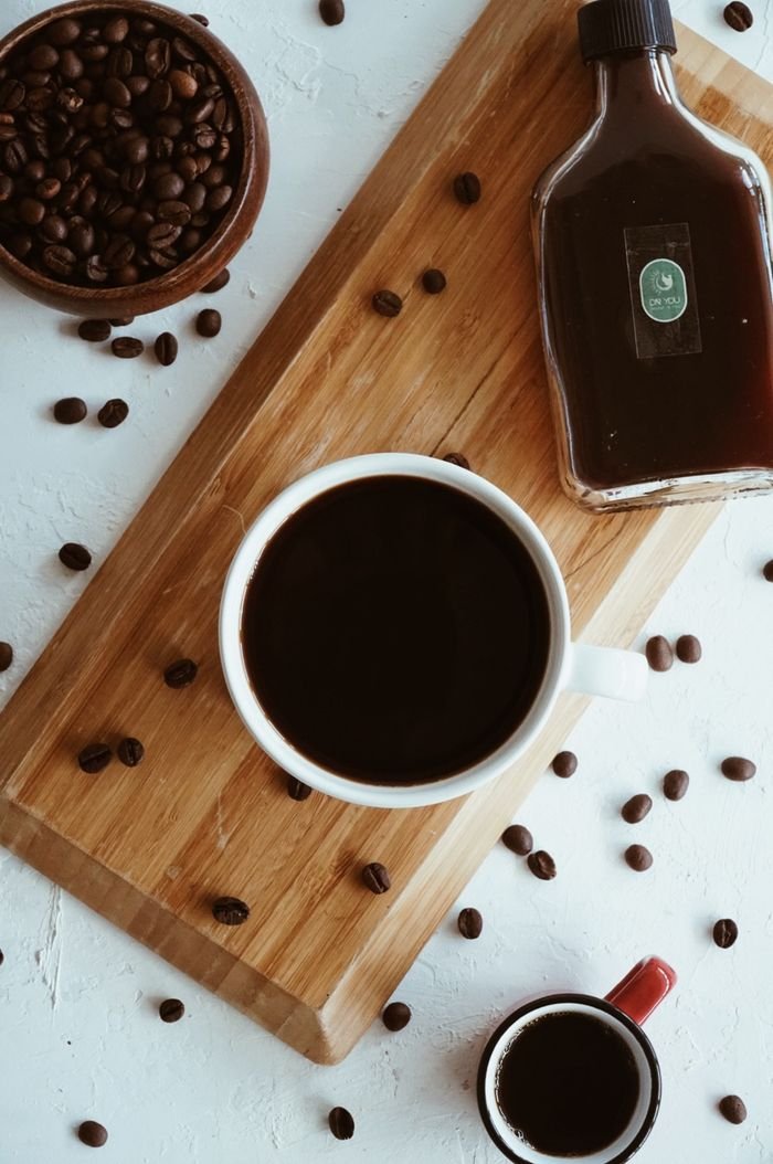 services-01 Coffee cups and a syrup bottle on a wooden board with scattered beans. Perfect for food photography.