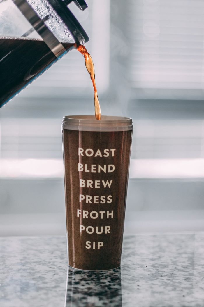 who-we-are Coffee being poured into a tumbler with inspirational coffee-related text written vertically.