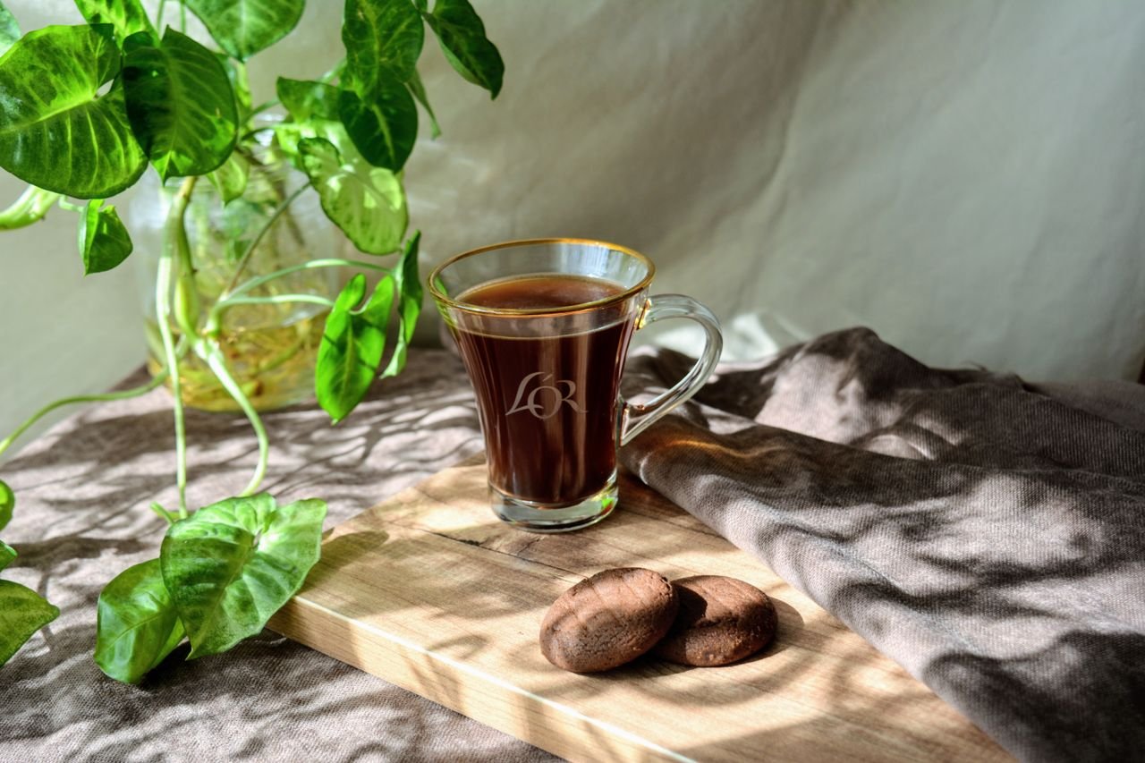 Crafting Captivating Headlines: Your awesome post title goes here A cup of black coffee with cookies in sunlight on a wooden table, surrounded by greenery.